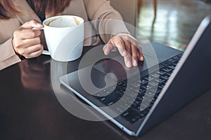 Hands using and touching on laptop touchpad while drinking coffee in cafe