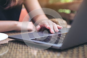 Hands using and touching on laptop touchpad on wooden table