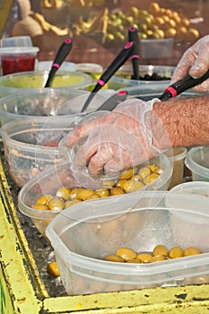 Hands of a vender scooping olives into a container at a farmers market photo