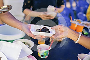 Hands of volunteers serves free food to the poor and needy in the city : The poor people bring a container to scoop food to eat