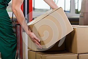 Hands of warehouse worker lifting box