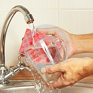 Hands wash the glass over the sink in kitchen