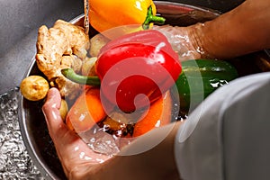 Hands wash vegetables in water.