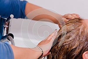 Hands washing with shampoo a long dyeing hair, inside a hairdressing saloon
