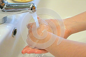 Hands washing under the water of a tap