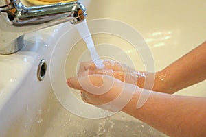 Hands washing under the water of a tap