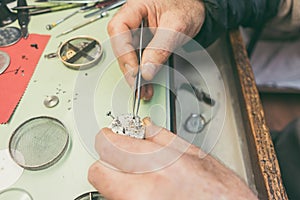 Hands of watchmaker fixing a watch in close-up