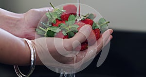 Hands, water and a person washing strawberries in the kitchen sink of a home closeup for hygiene. Food, diet and