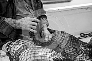 Hands of weathered fisherman mending net