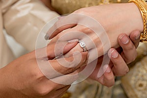 hands of a wedding couple, Groom put a ring on finger of his lov