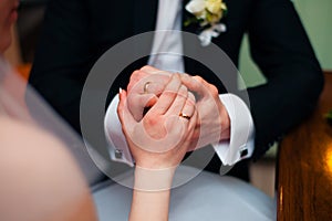 Hands of wedding couple putting golden rings to finger of each other.