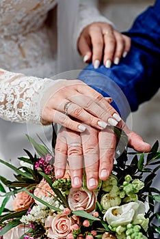 Hands with wedding gold rings happy newlyweds on a the bouquet background.