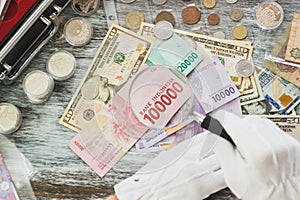 Hands in white gloves, different American dollars and Indonesian rupiahs, numismatics concept