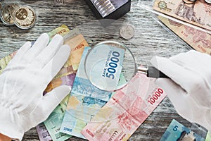 Hands in white gloves, different American dollars and Indonesian rupiahs, numismatics concept