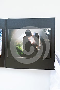 Hands in white gloves flipping through a photo book with wedding photos