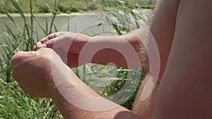 Hands of white man with hairy body baiting worm on hook. Close up view.