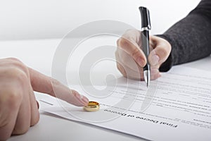 Hands of wife, husband signing decree of divorce, dissolution, canceling marriage, legal separation documents, filing