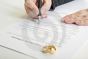 Hands of wife, husband signing decree of divorce, dissolution, canceling marriage, legal separation documents, filing