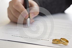 Hands of wife, husband signing decree of divorce, dissolution, canceling marriage, legal separation documents, filing