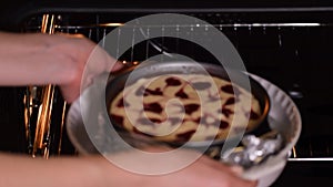 Hands of woman baker putting in the oven a homemade cheesecake.