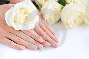 Hands of a woman with beautiful french manicure and white roses