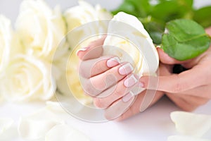 Hands of a woman with beautiful french manicure and white roses