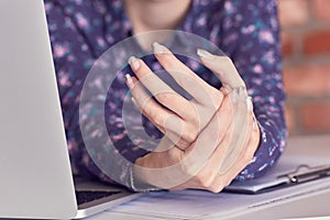 Hands of woman with carpal tunnel syndrome over computer keyboard close-up.