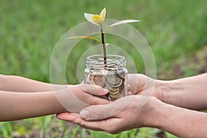 Hands of woman and child is holding coins money in glass jar