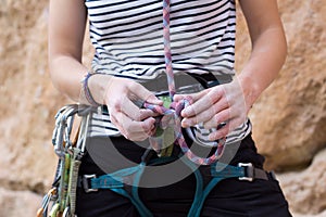 Hands of a woman climber, in magnesium powder, making an eight knot in the rope to start climbing