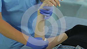 The hands of a woman in a cometologist prepare the skin for a shugaring procedure.