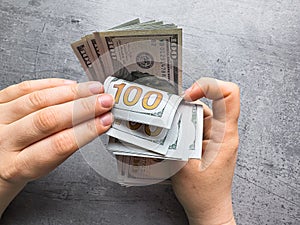 Hands of woman counting dollars on desk. Salary accrual or deferment of funds for a future purchase