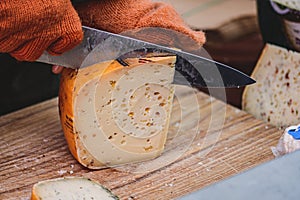 Hands of woman cutting with a knife a slice of homemade bio natural cheese