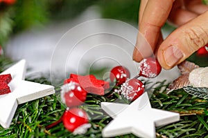 Hands of a woman decorate Christmas Advent wreath from fir twigs