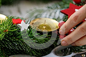 Hands of a woman decorate Christmas Advent wreath from fir twigs