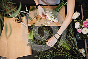 Hands of woman florist creating flower bouquet on table