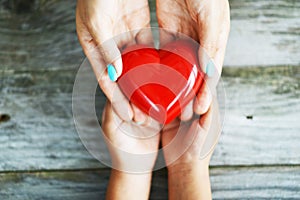 Hands of woman giving a shiny red heart to her daughter, sharing love concept