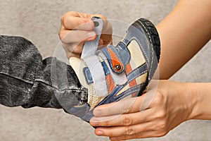 Hands of woman helping child to put shoes