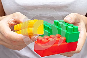 Hands of a woman holding colorful toy plastic bricks, blocks for building, playing games and entertainment concept