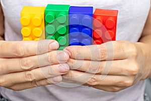 Hands of a woman holding colorful toy plastic bricks, blocks for building, playing games and entertainment concept