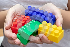 Hands of a woman holding colorful toy plastic bricks, blocks for building, playing games and entertainment concept