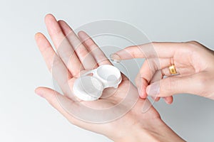 Hands of woman holding contact lenses cases and lens