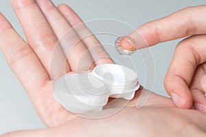 Hands of woman holding contact lenses cases and lens