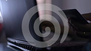 Hands of a woman holding a credit card and typing laptop keyboard for online payment.