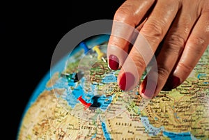 Hands of a woman holding a globe of the planet earth with marked places to travel on vacation