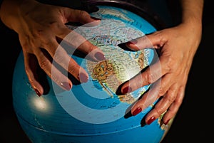 Hands of a woman holding a globe of the planet earth with marked places to travel on vacation
