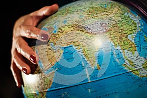 Hands of a woman holding a globe of the planet earth with marked places to travel on vacation