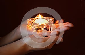 Hands of a woman holding a lit tea light in star shape