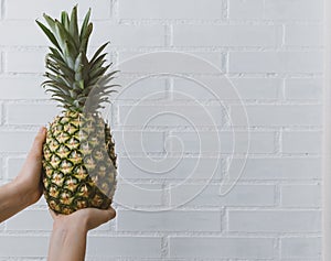 Hands of a woman holding a pineapple and space for copy text