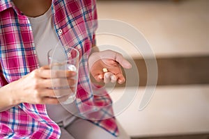 Close up of woman holding a glass of water and pills