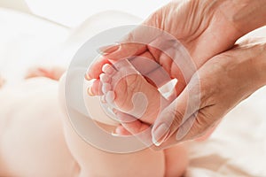 Hands of woman holds baby feet